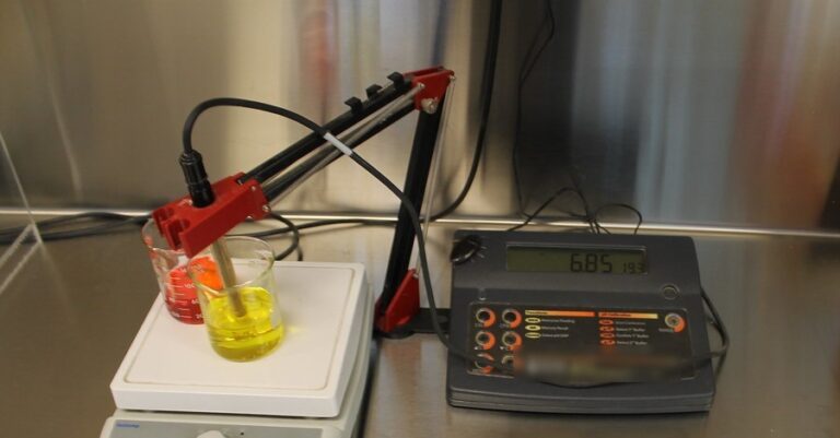 Bench pH meter with its probe in a colored calibration buffer, reading 6.85