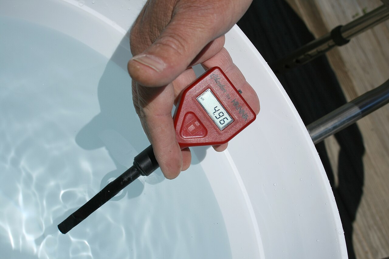 pH pen reading 4.96 in a nutrient reservoir, a sign to raise pH in hydroponics